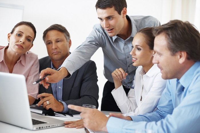 Business team discussing project with man pointing at the laptop